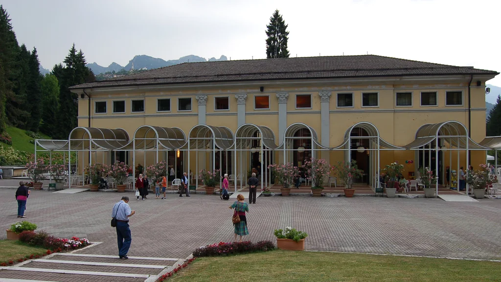 Edificio delle Terme di Recoaro con piazzale fiorito e rilievi delle Piccole Dolomiti sullo sfondo